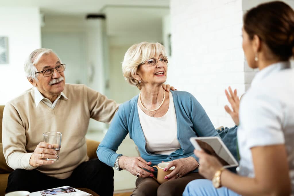 Barton House Memory Care | Seniors speaking with associate holding tablet