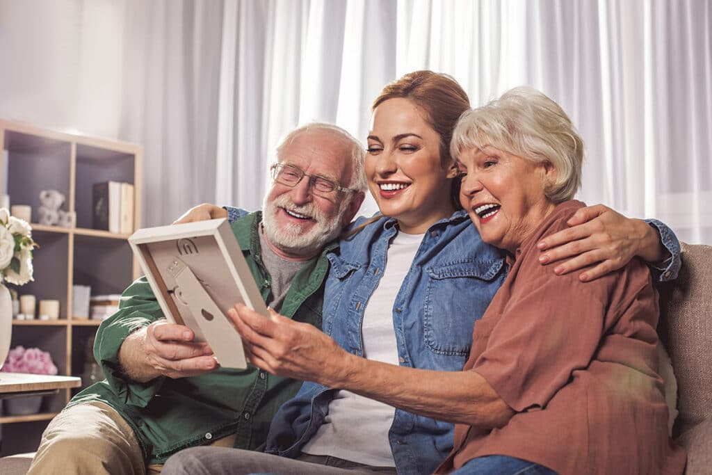 Barton House Memory Care | Senior couple looking at photograph with adult daughter