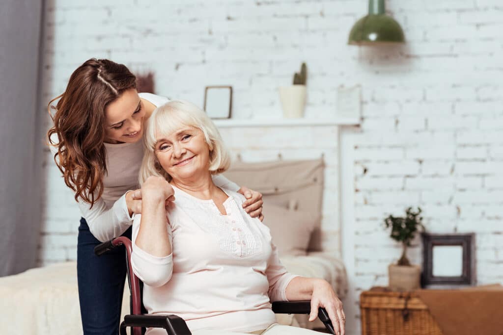 Novellus Barton House | Cheerful elderly woman sitting in the wheelchair with caretaker