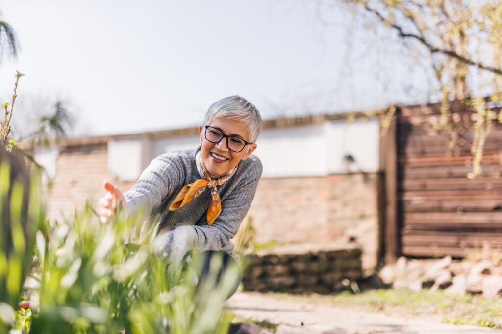 Novellus Clairemont | Happy senior woman looking at flowers