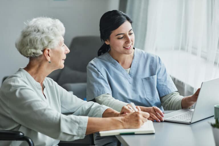 Novellus Cypresswood | Senior woman talking with her caregiver and going over paperwork