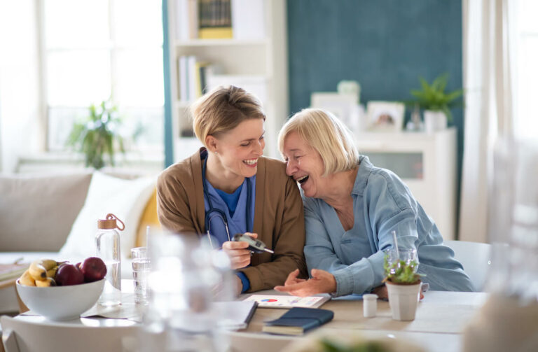 Novellus Kingwood | Senior woman laughing next to her caregiver after a checkup