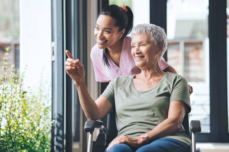 Novellus Kingwood | Shot of a young nurse standing beside an older woman in a wheelchair.