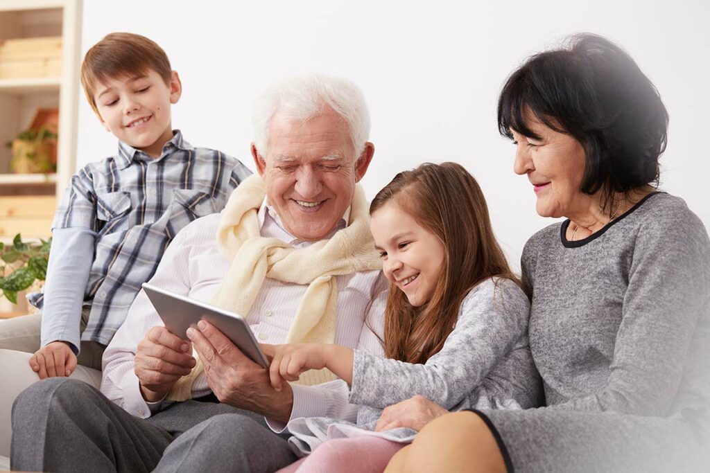Novellus Kingwood | A senior and his grandkids looking at a photo