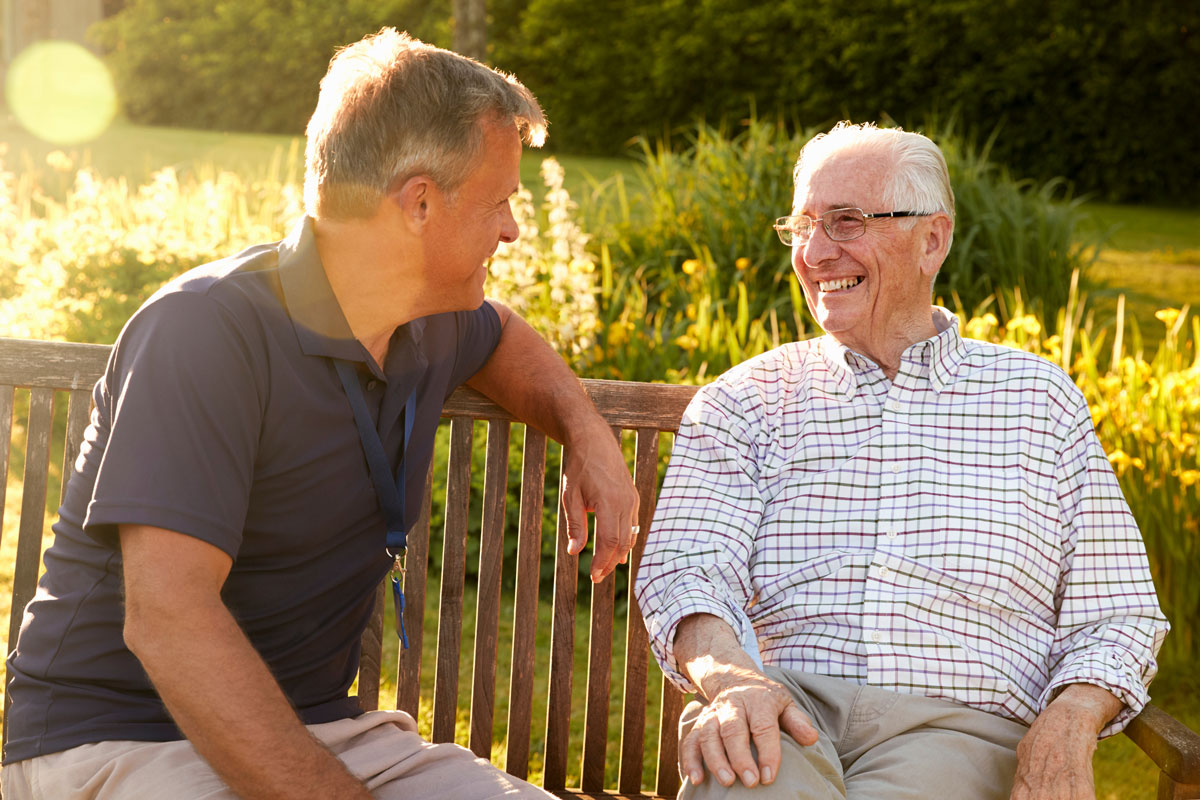 Novellus Kingwood | Senior man lauging with his friend on a park bench