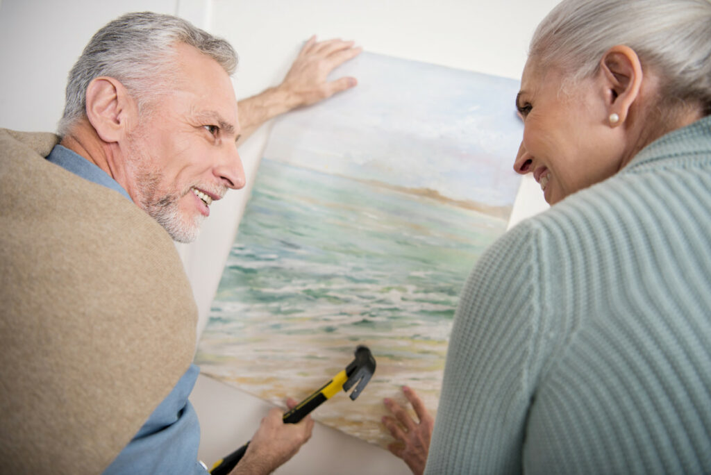 Novellus Kingwood |Senior couple hanging a picture on the wall together