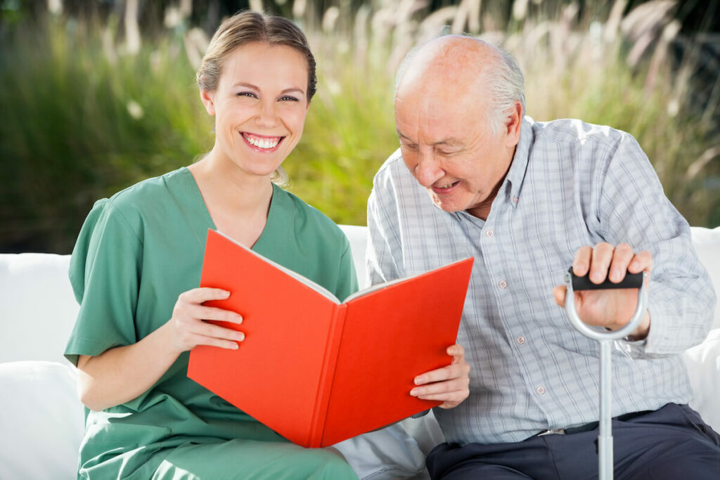 Orangeburg | Happy Senior man looking at a book with his caregiver