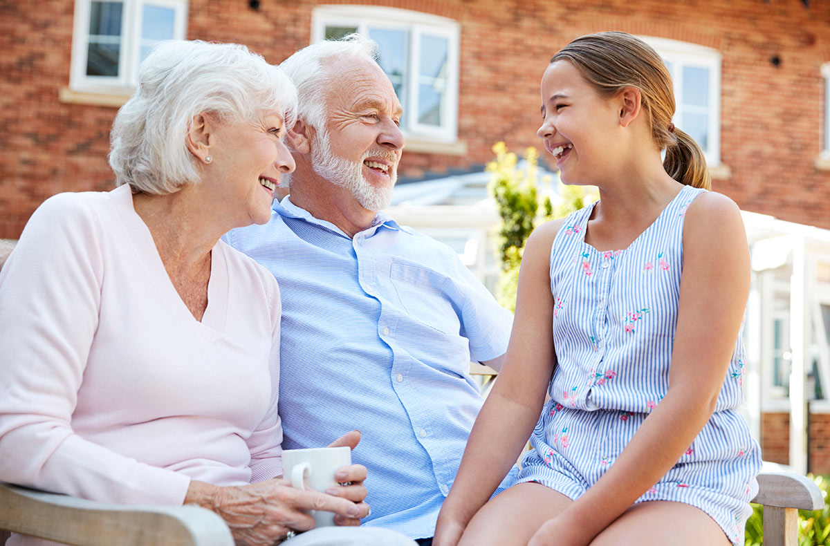 Stockton Assisted Living | Senior grandparents sitting with granddaughter on a bench