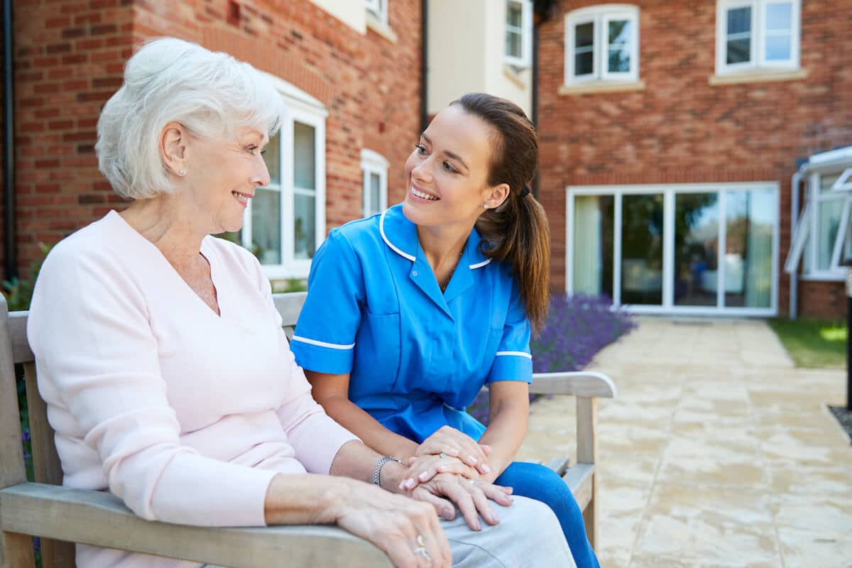 Orangeburg | Happy senior and caregiver sitting outside together