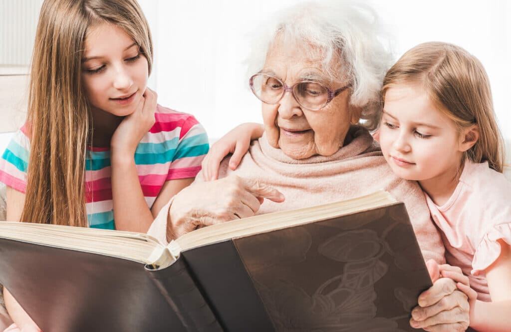Barton House Memory Care | Senior woman and her grandkids looking through photos