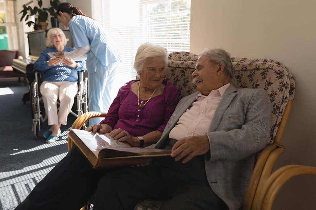 Barton House | Front view of senior couple looking photo album on sofa