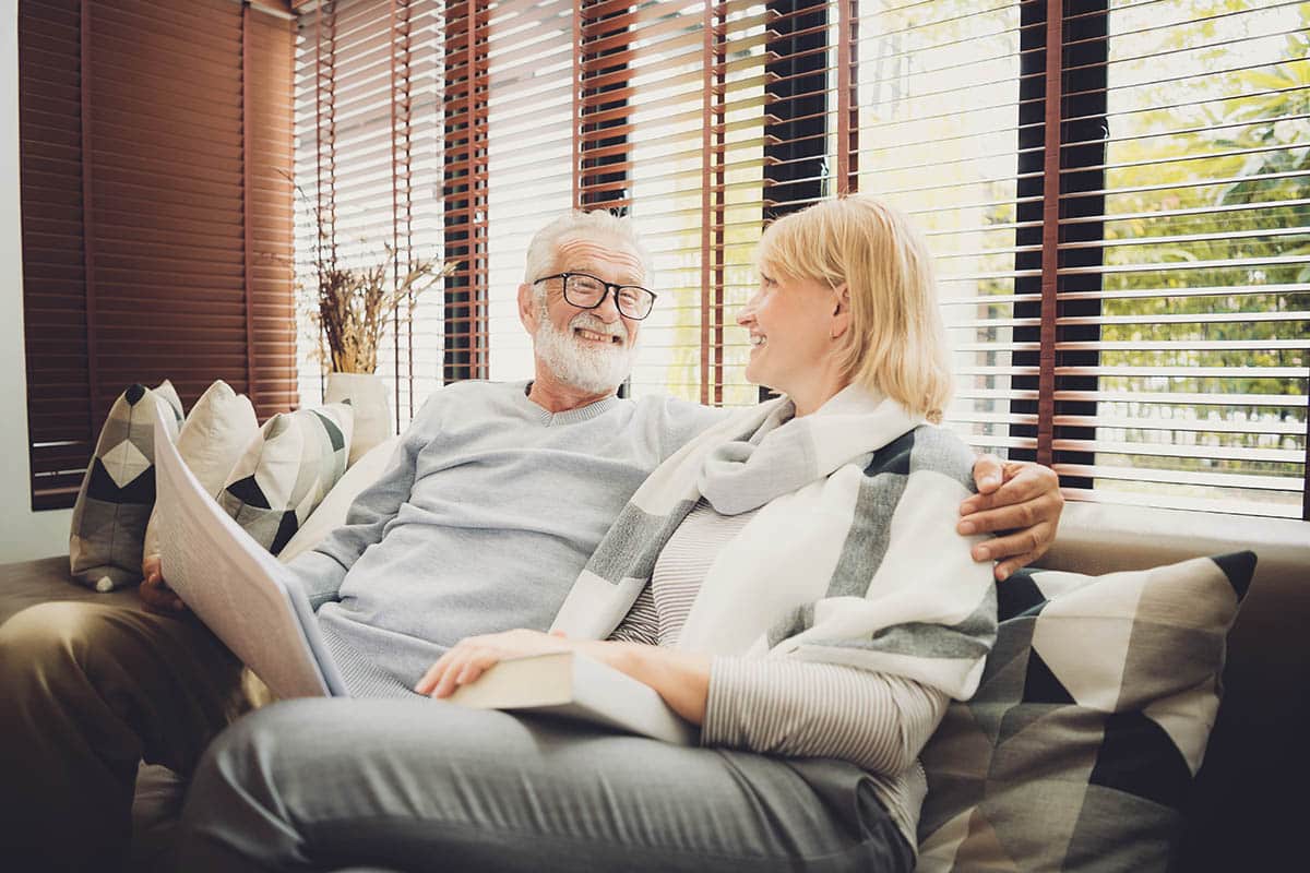 Camlu Assisted Living | Happy senior couple sitting at sofa in living room and reading