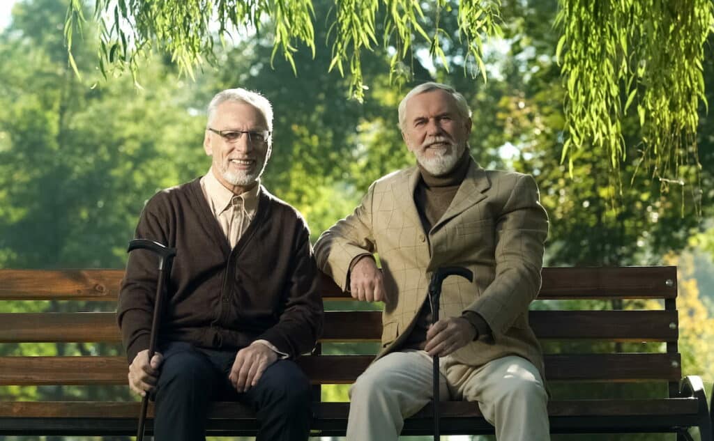 Cherry Creek | Two senior men sitting on bench outside underneath a tree