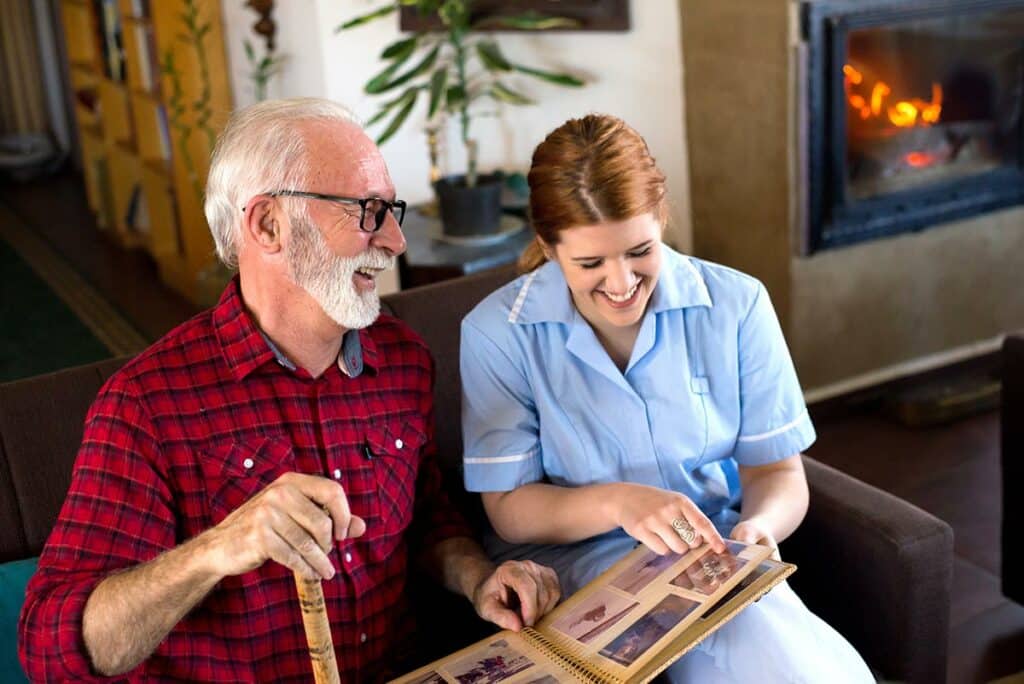 Orangeburg Memory Care | Senior and caregiver look at photo album
