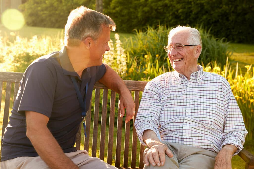 Novellus Kingwood | Senior man lauging with his friend on a park bench