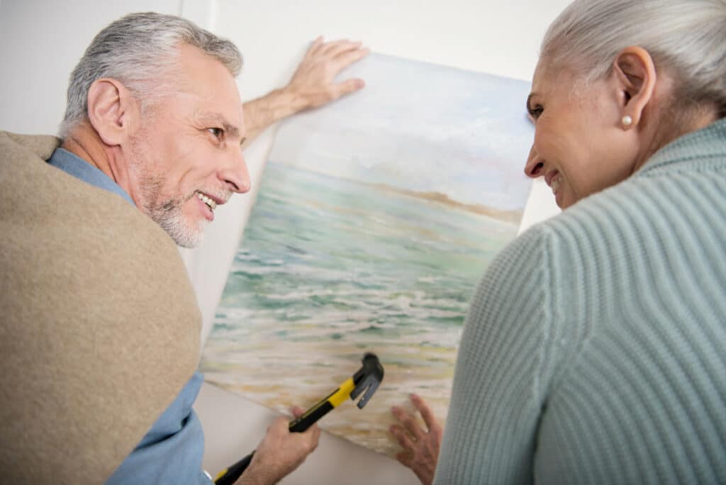 Novellus Camlu | Senior couple hanging a picture on the wall together